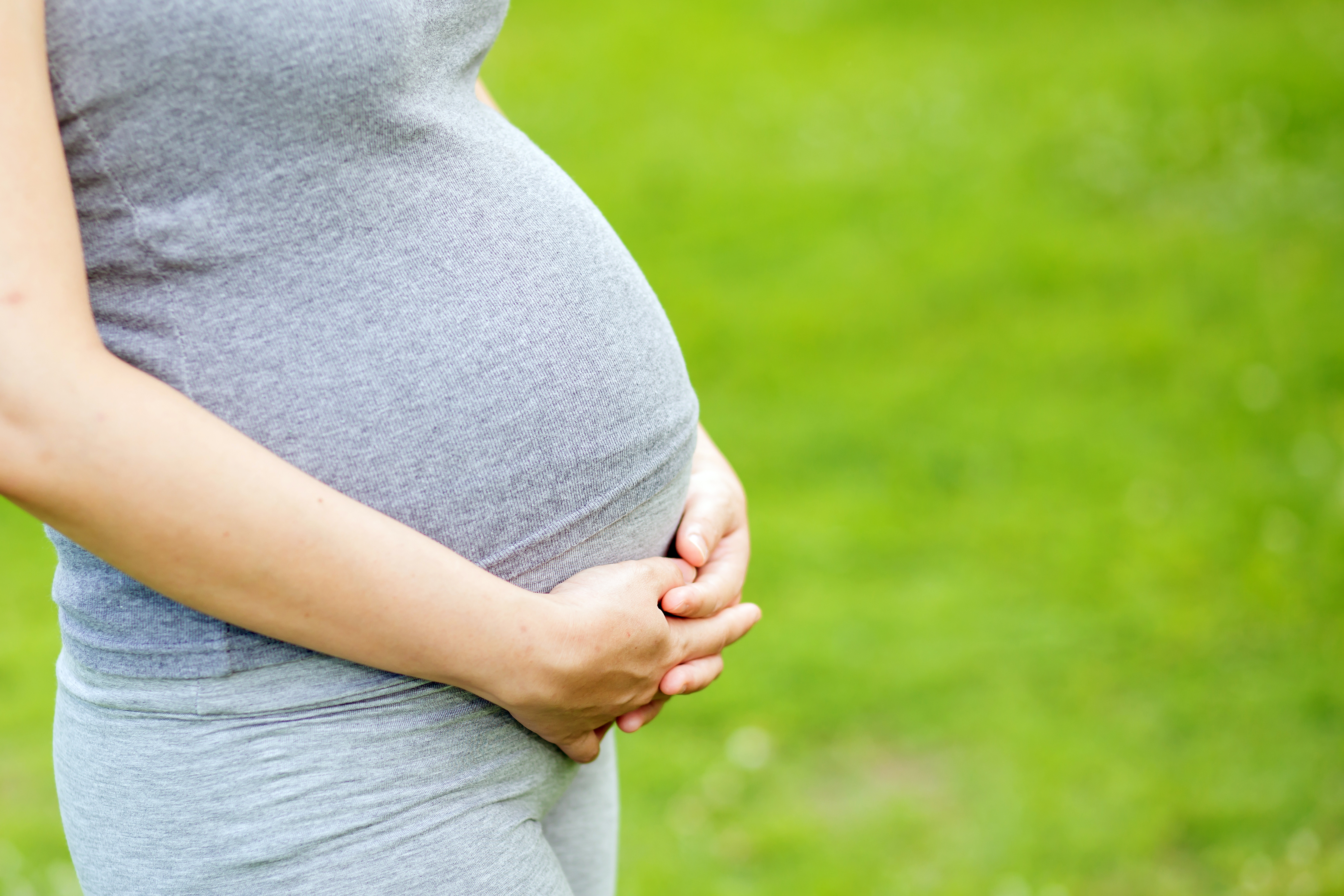Pregnant woman standing outside on a sunny day
