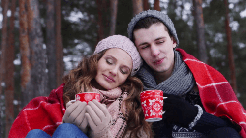 young-couple-sitting-by-bonfire-and-drinking-coffee-in-winter-forest_swx3rzoowl_thumbnail-full01