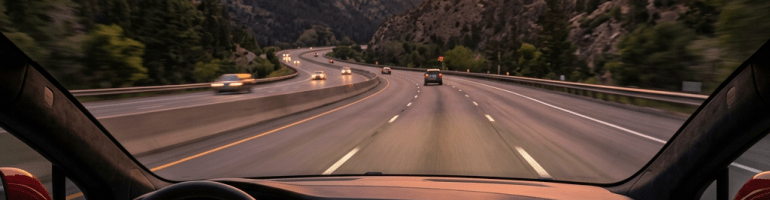 Interior view of Tesla dashboard and steering wheel driving on highway with mountain sunset